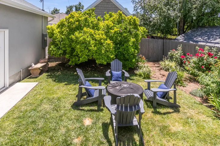 Expansive backyard featuring a manicured lawn, established shrubbery, a concrete walkway, and a privacy fence