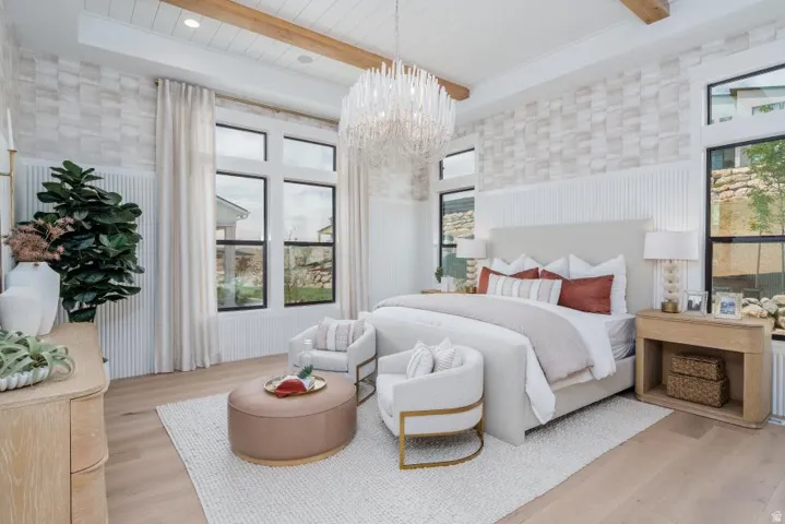 Bright, light-filled primary bedroom featuring exposed wood ceiling beams, white subway tile accent walls, and large multi-pane windows with operable shutters