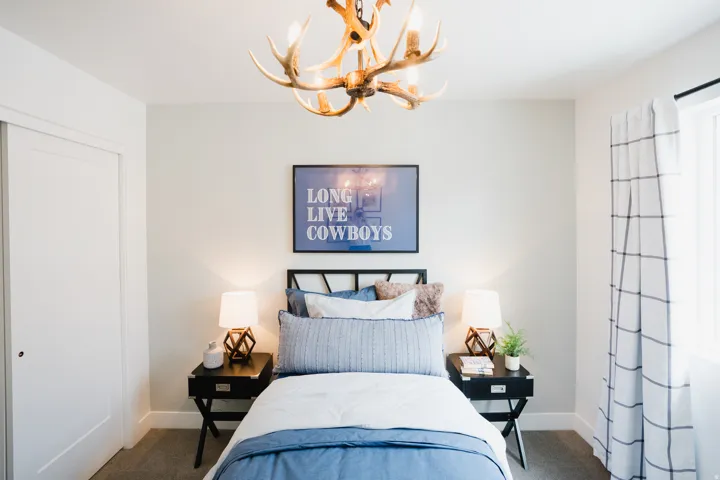Bedroom featuring a unique antler chandelier, a white sliding closet door, and a window with plaid drapes