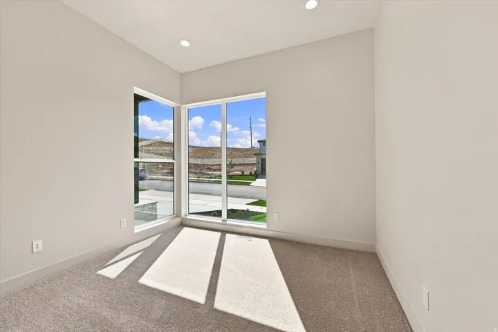 Corner window arrangement, recessed ceiling lighting, light-toned walls, and carpeted flooring