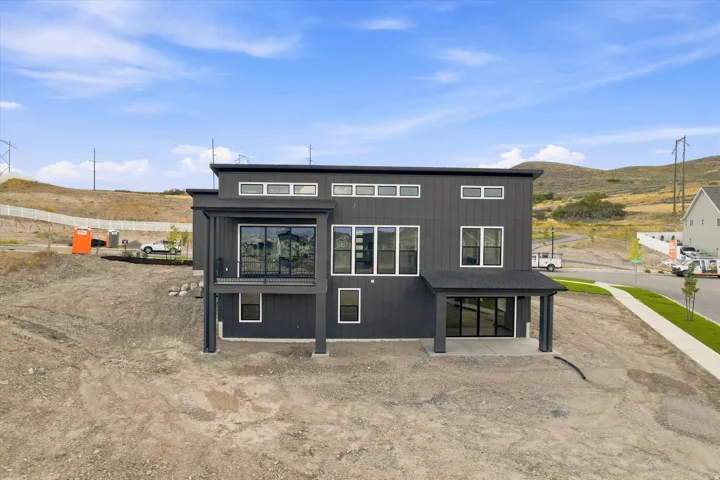 Modern exterior with dark vertical siding, multiple large windows, and a covered patio
