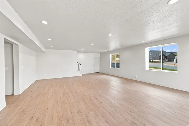 Spacious room featuring wood-finish flooring, recessed lighting, and multiple windows