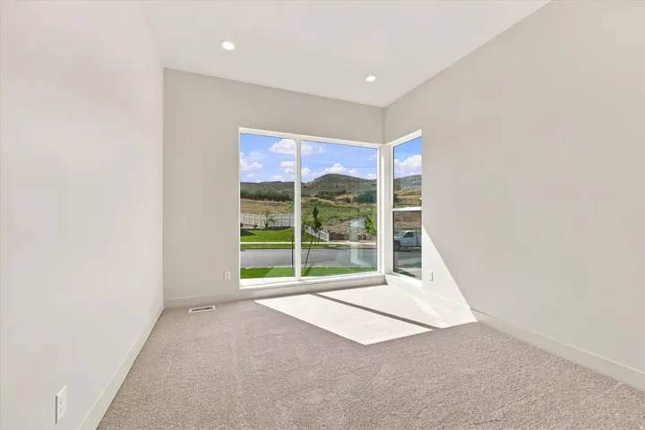 Expansive corner windows, recessed lighting, neutral carpeting, and painted walls
