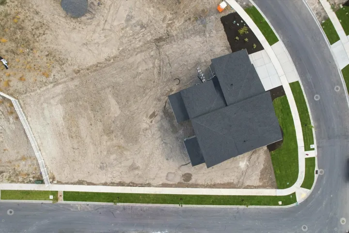 Newly constructed residence with a dark shingle roof, expansive lot, established curbing, and fresh landscaping