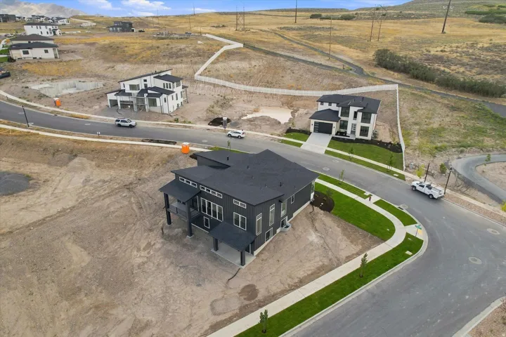 Contemporary architecture featuring a dark facade, covered porch, multiple large windows, and a paved driveway