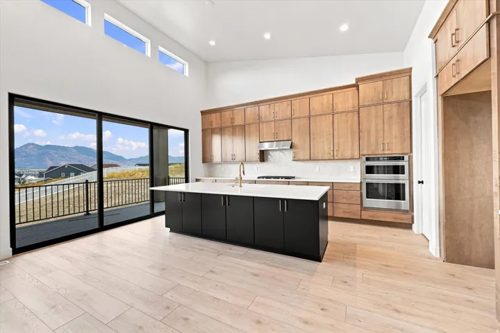 Kitchen with wood-finish flooring, a central island featuring a white countertop, and extensive cabinetry