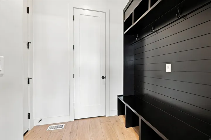 Built-in storage bench with overhead cubbies, integrated coat hooks, and durable wood-finish flooring