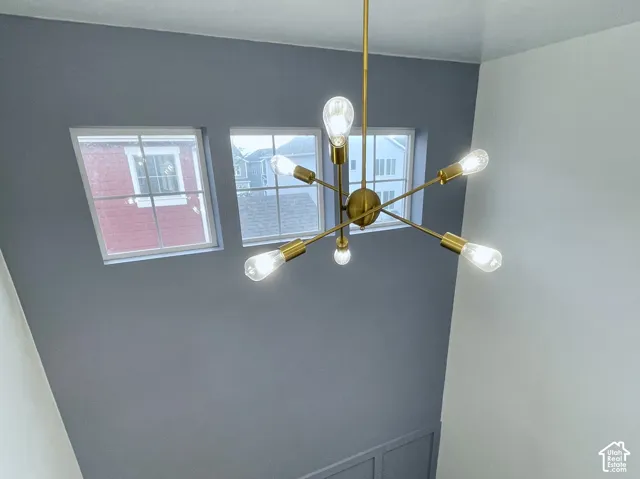 Contemporary chandelier illuminating a carpeted stairway with wainscoting and natural light from upper windows