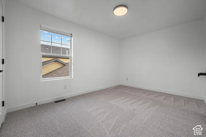 Room featuring light gray patterned carpet, white baseboards, and a single window with white trim
