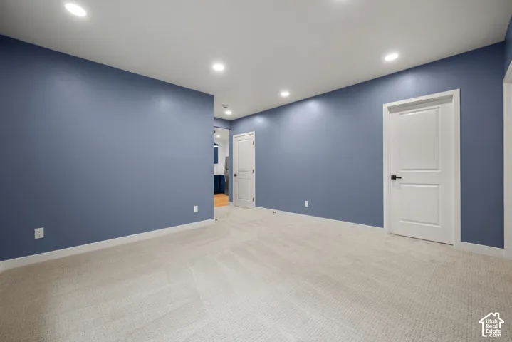 Spacious room featuring neutral carpeting, blue accent walls, white trim, recessed lighting, and white two-panel doors with black hardware
