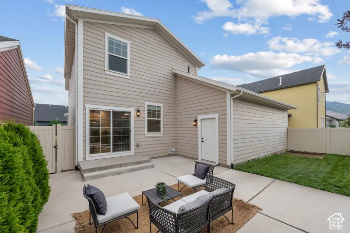 Rear exterior featuring horizontal siding, a sliding glass door, and a concrete patio