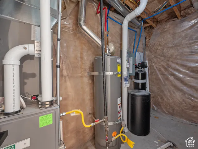 Dedicated utility area featuring a water heater, furnace, and water conditioning system, all installed on a concrete floor