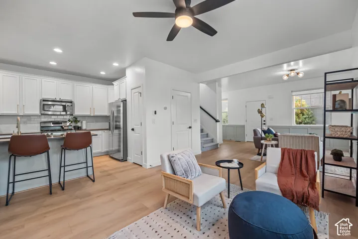 Open-concept living area featuring wood-finish flooring throughout, a modern ceiling fan, and recessed lighting