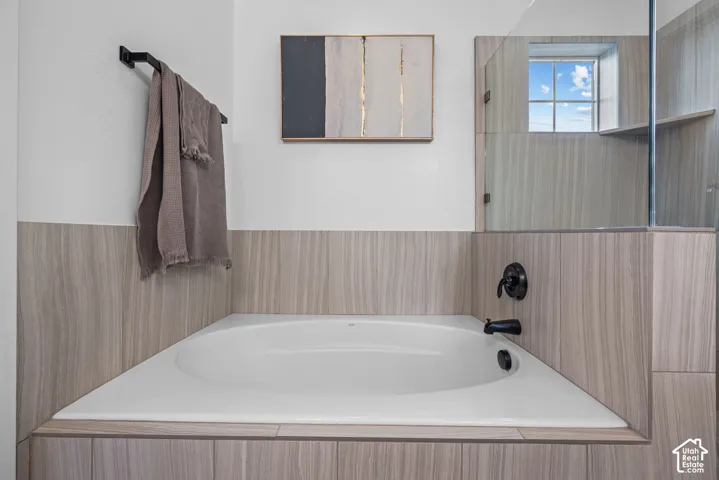 Built-in soaking tub with dark bronze fixtures set against wood-finish tile surround