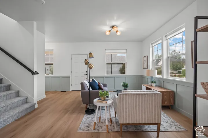 Bright living area featuring wood-finish flooring, wainscoting, and multiple windows