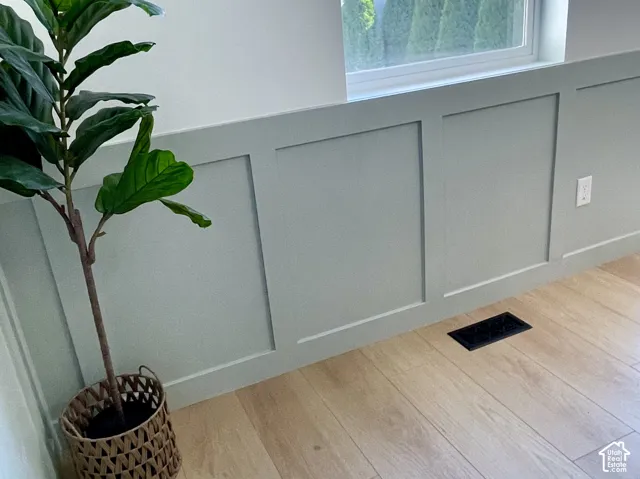 Window-framed setting featuring light wood-finish flooring, a contemporary board and batten wall treatment, and a painted wall finish