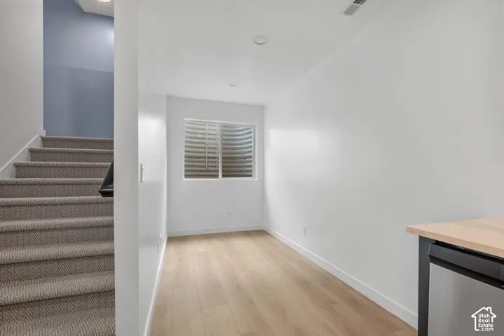 Finished room featuring wood-finish flooring, recessed lighting, and a built-in beverage refrigerator with a wood countertop