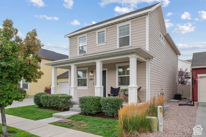 Two-story residence featuring light beige siding and a covered front porch with white columns