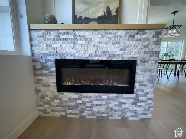 Modern electric fireplace with realistic flame effect and glowing ember bed, set within a striking linear surround of stacked stone tile in neutral gray and white tones