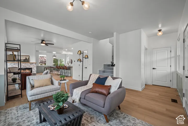 Open-concept living space featuring wood-finish flooring, a stone-clad fireplace, and recessed lighting