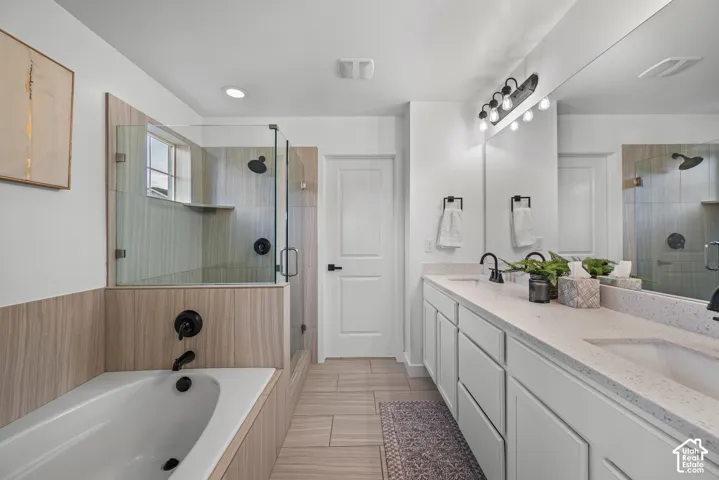 Spacious bathroom featuring a glass-enclosed shower with tiled walls, a separate built-in soaking tub, and a double vanity with two integrated sinks