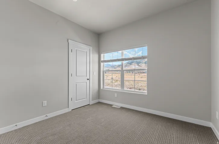 Room featuring neutral wall finishes, a multi-pane window, carpet flooring, and a paneled door