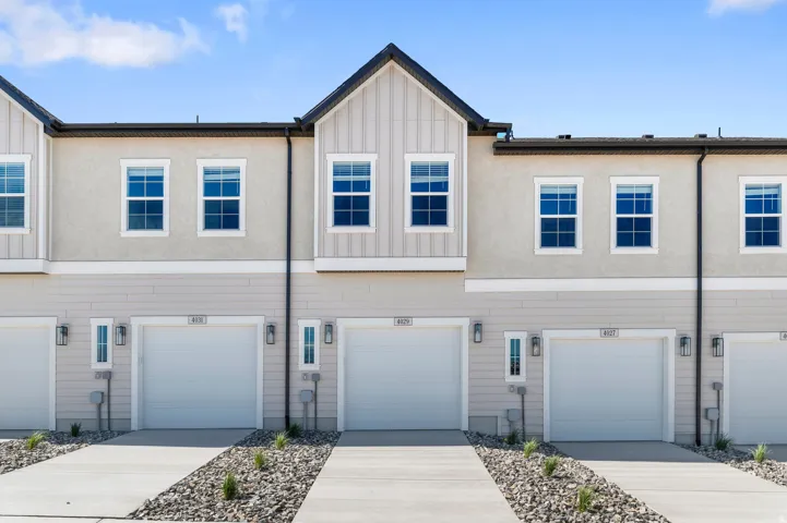 Contemporary townhome exterior featuring light-colored siding, stucco accents, and white-framed windows