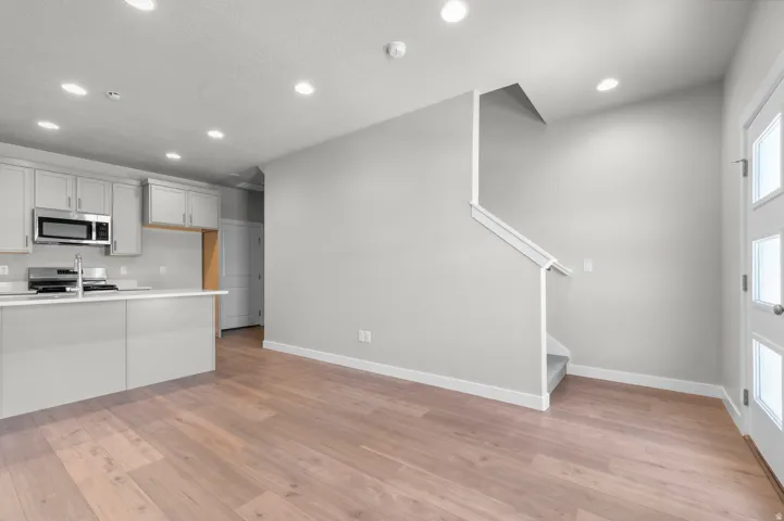 Open-concept layout with wood-finish flooring, recessed lighting, and a modern kitchen featuring stainless steel appliances and light gray cabinetry