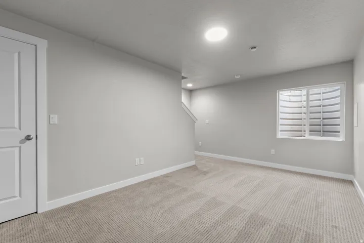 Recessed lighting, light gray wall paint, window with egress well, and light-toned carpeting