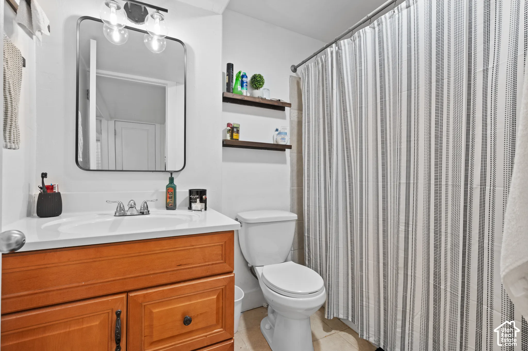 Bathroom featuring a wood-finish vanity with a white countertop and integrated sink, framed mirror, and a chrome light fixture