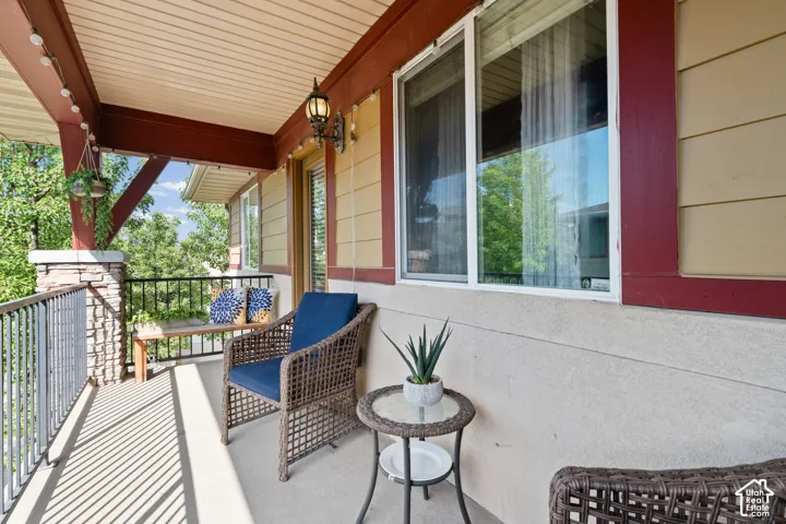 Covered outdoor patio featuring a textured ceiling, a wrought iron railing, and a stone pillar accent