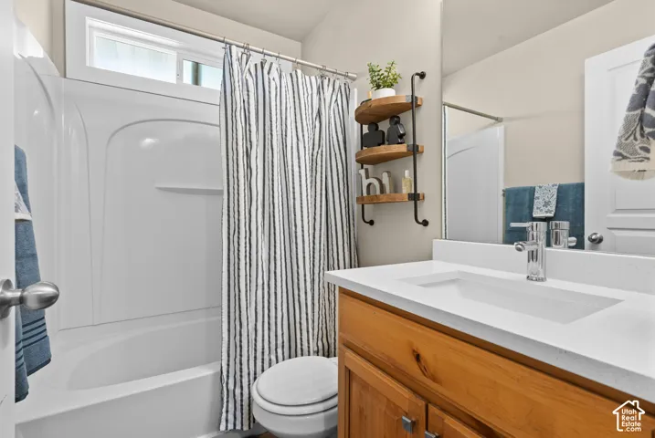 Bathroom featuring a white integrated sink with a single-handle chrome faucet, a wood-finish vanity, and a white fiberglass shower-tub combination