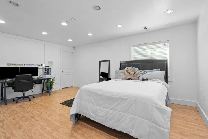 Spacious room featuring wood-finish flooring, recessed lighting, and a window with blinds