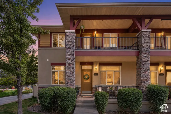 Exterior featuring stacked stone masonry columns, a covered balcony with metal railing, and a covered front porch