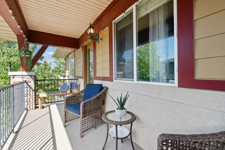 Covered outdoor patio featuring a textured ceiling, a wrought iron railing, and a stone pillar accent