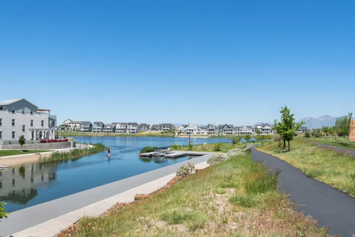 Expansive waterfront community featuring a paved walking path, mature landscaping, and a dock structure