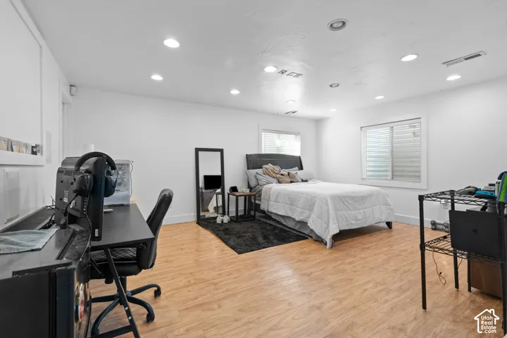Spacious room featuring light wood-finish flooring, recessed lighting, and white walls