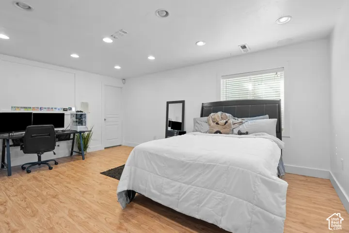 Spacious room featuring wood-finish flooring, recessed lighting, and a window with blinds