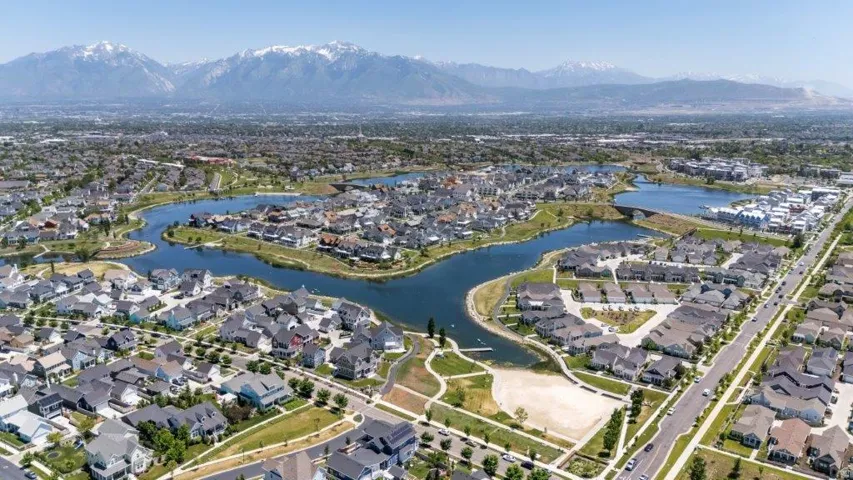 Aerial overview of a residential community featuring a central lake and surrounding homes with varied architectural styles
