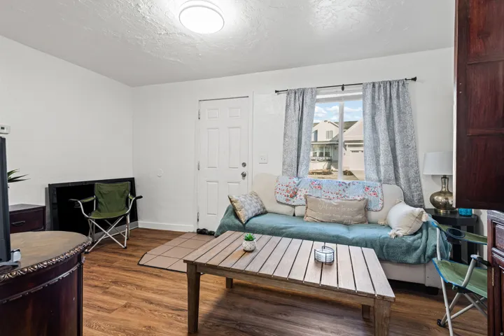 Living area featuring wood-finish flooring, a white paneled entry door, and a multi-paned window