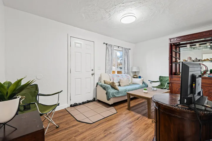 Living area featuring wood-finish flooring, white walls, and a window with natural light