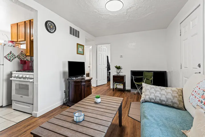 Open-concept living area featuring wood-finish flooring, white walls, and a recessed kitchen
