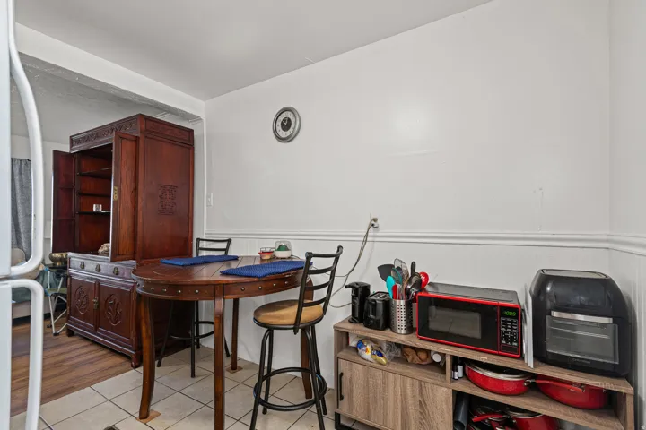 Compact dining area featuring tile flooring, white wainscoting, and a built-in wood-finish hutch