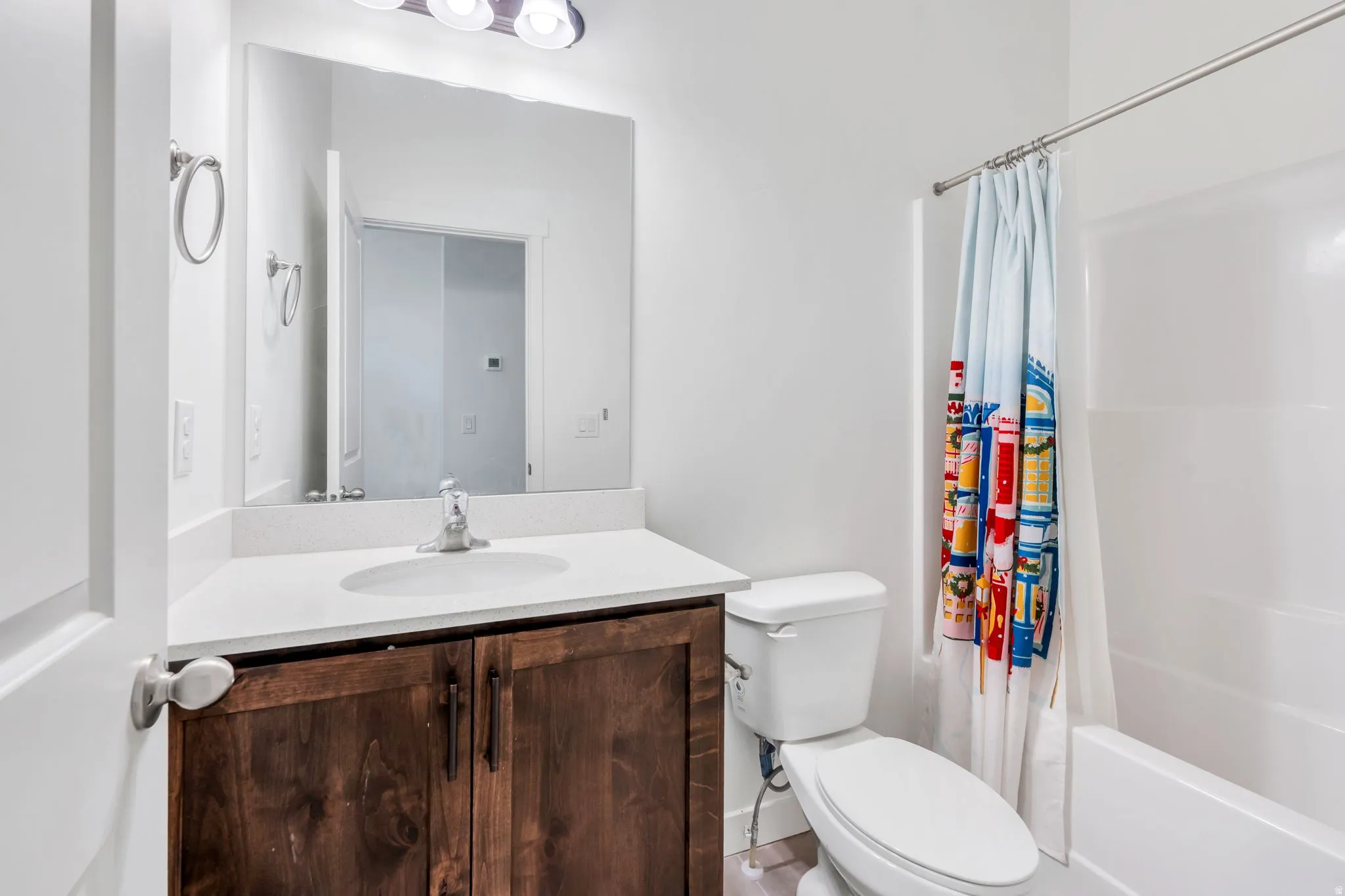 Bathroom featuring a wood-finish vanity with a white countertop, an integrated sink, and a framed mirror