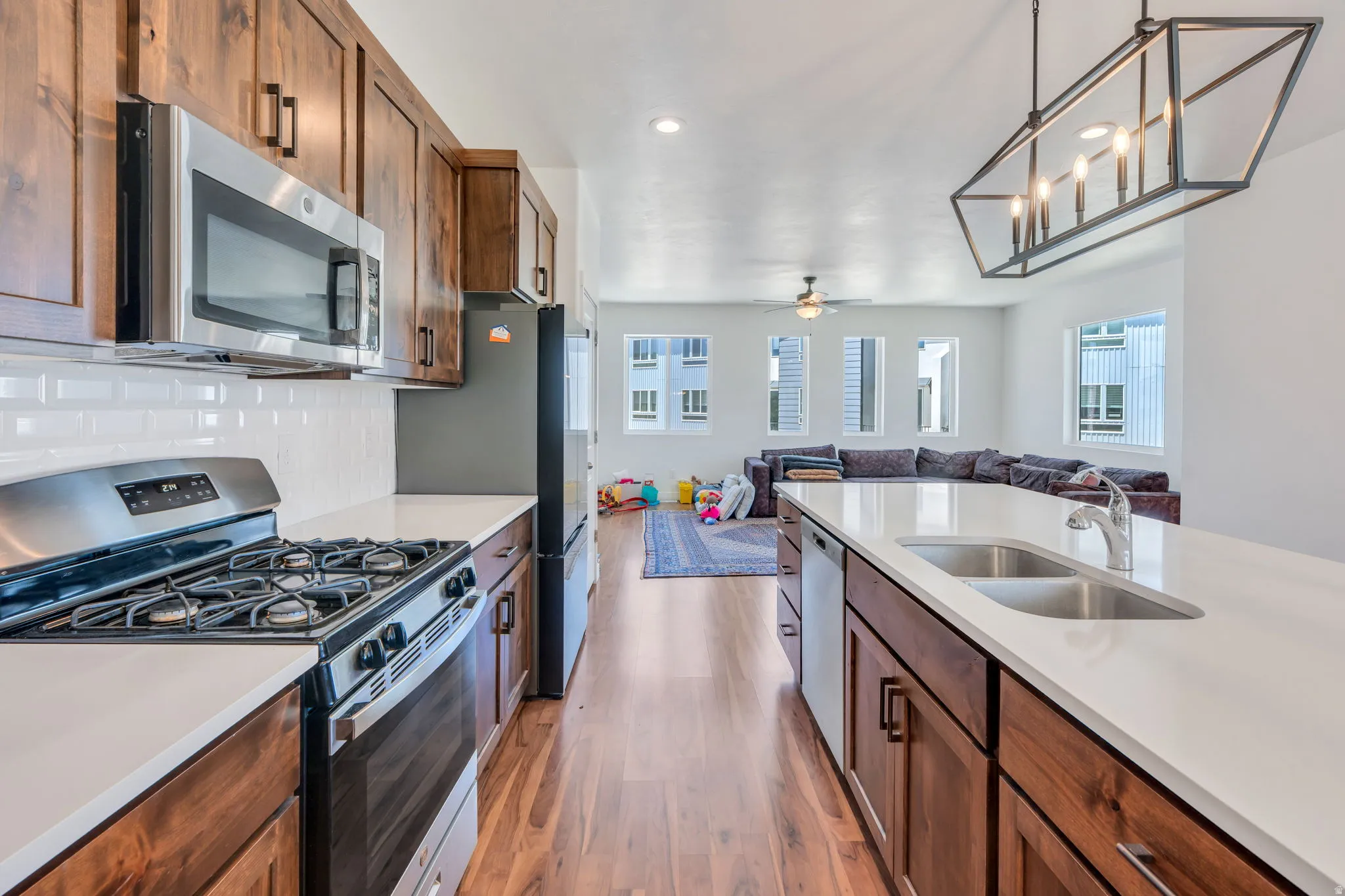 Modern kitchen featuring rich wood cabinetry, stainless steel appliances, and white subway tile backsplash
