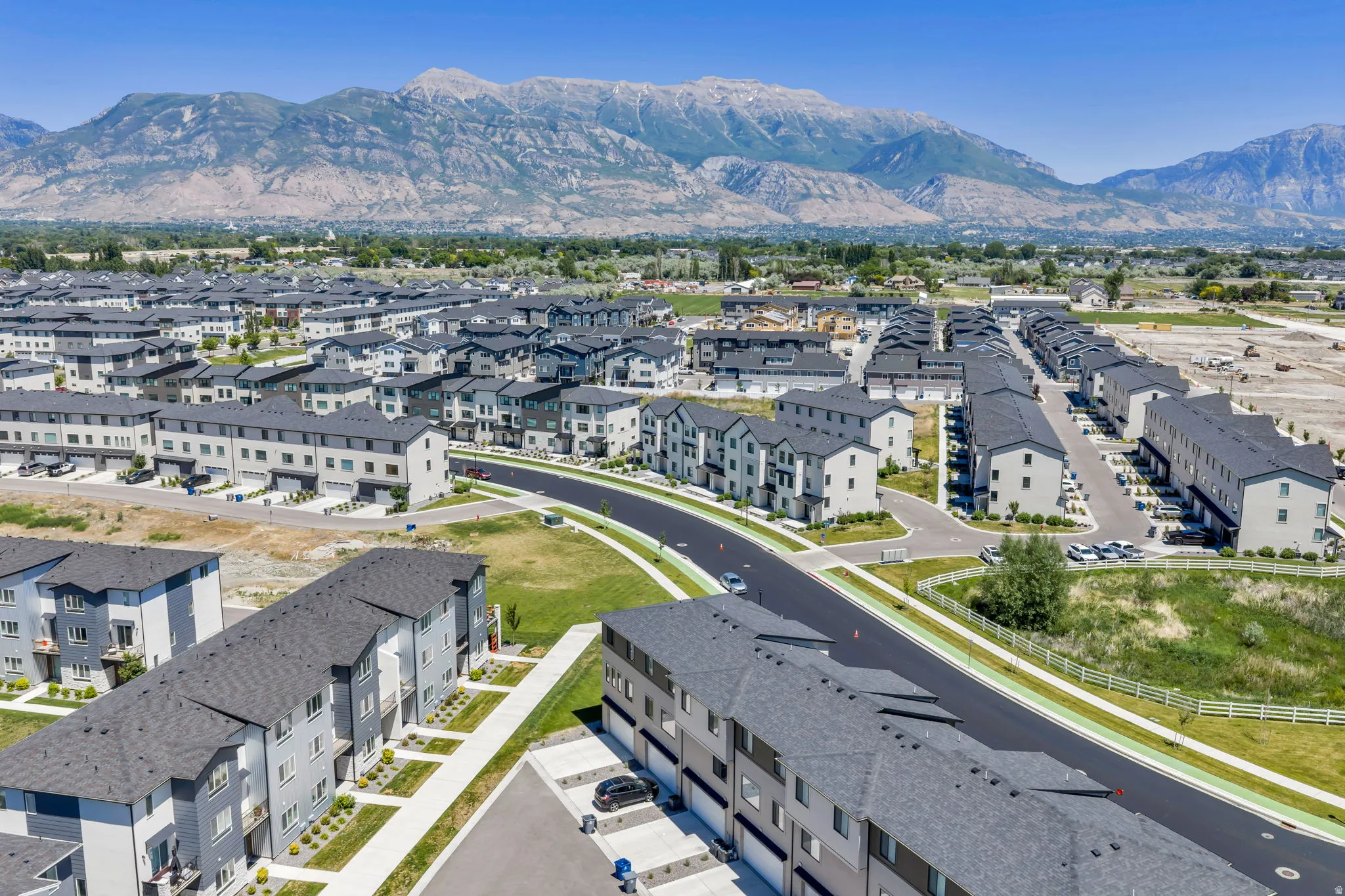 Expansive residential development featuring modern townhomes, paved roadways, and mountain backdrop