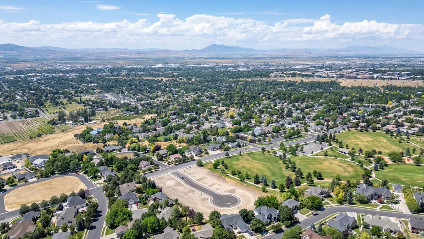Aerial perspective showcasing a developing residential area with established homes, green spaces, and mountain backdrops