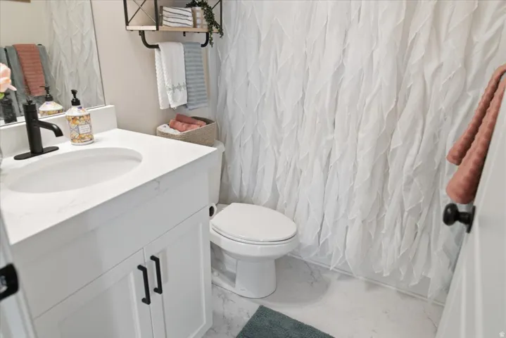 Bathroom featuring a white vanity with a solid surface countertop, an undermount sink, and a matte black faucet