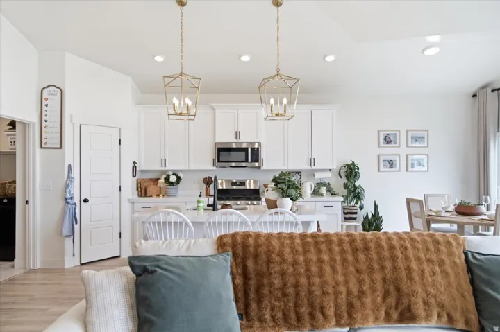 Open-concept kitchen and dining area featuring white cabinetry, stainless steel appliances, and a central island with seating