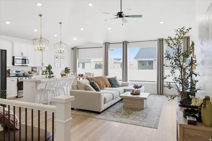 Open-concept living area with vaulted ceilings, wood-finish flooring, and recessed lighting